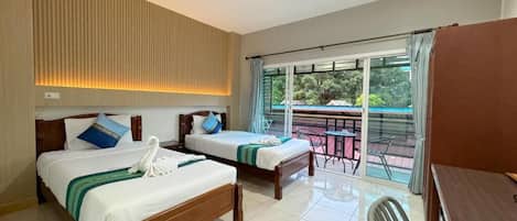 Quarto de hotel com duas camas, uma mesa de jantar e varanda com vista.
