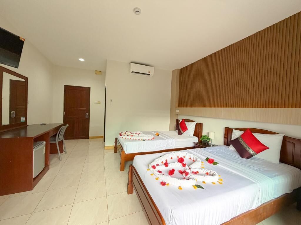 A hotel room with two beds, a desk, and a mirror.