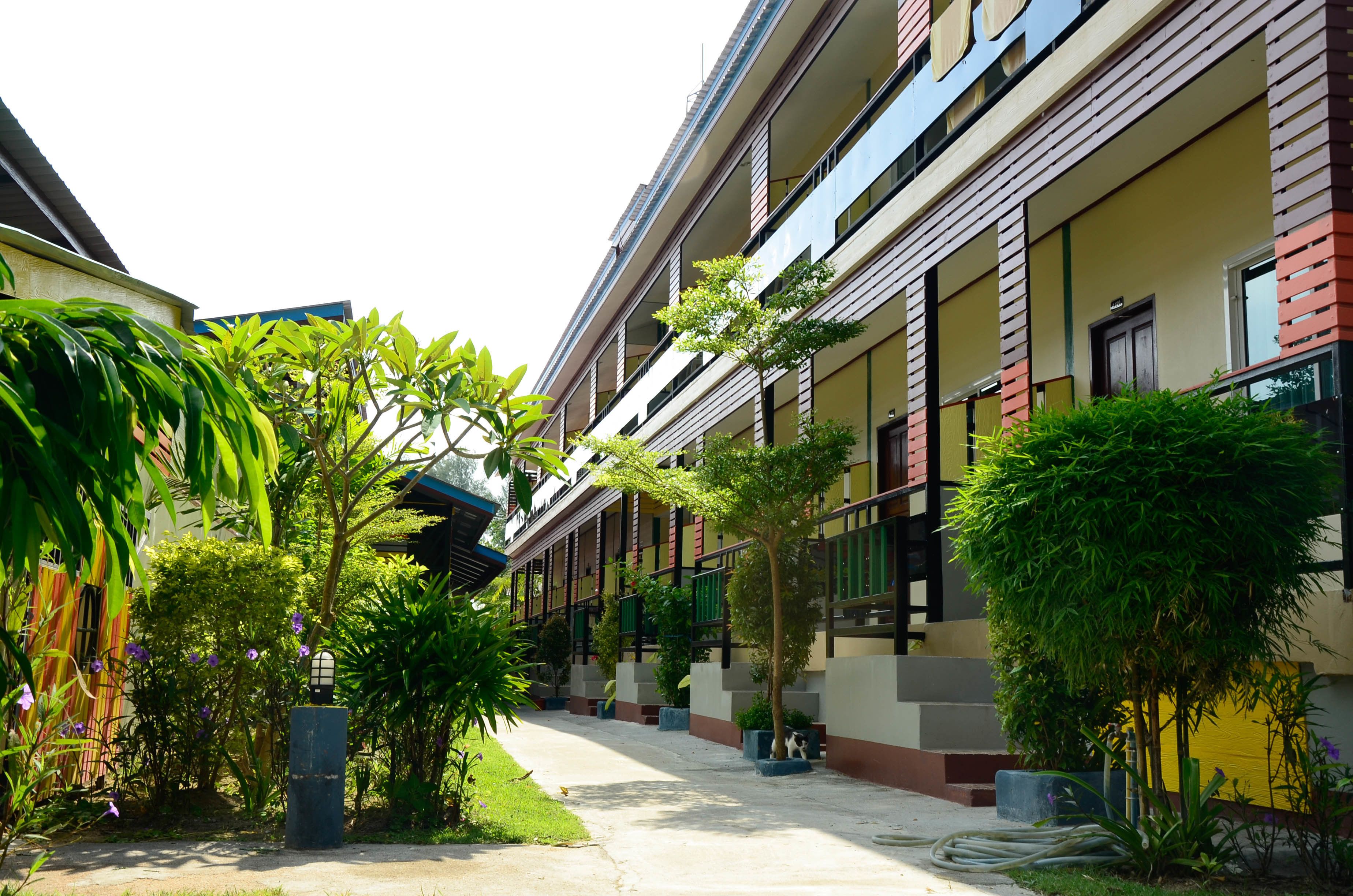 A corridor with a row of rooms, each with a balcony and a window.