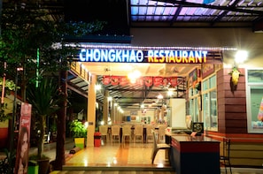 A restaurant with a neon sign, indoor seating, and a tiled floor. - Chongkhao Resort (Ko Phi Phi)