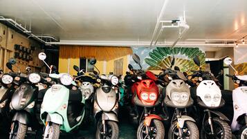 A row of scooters parked in a garage with a mural on the wall.