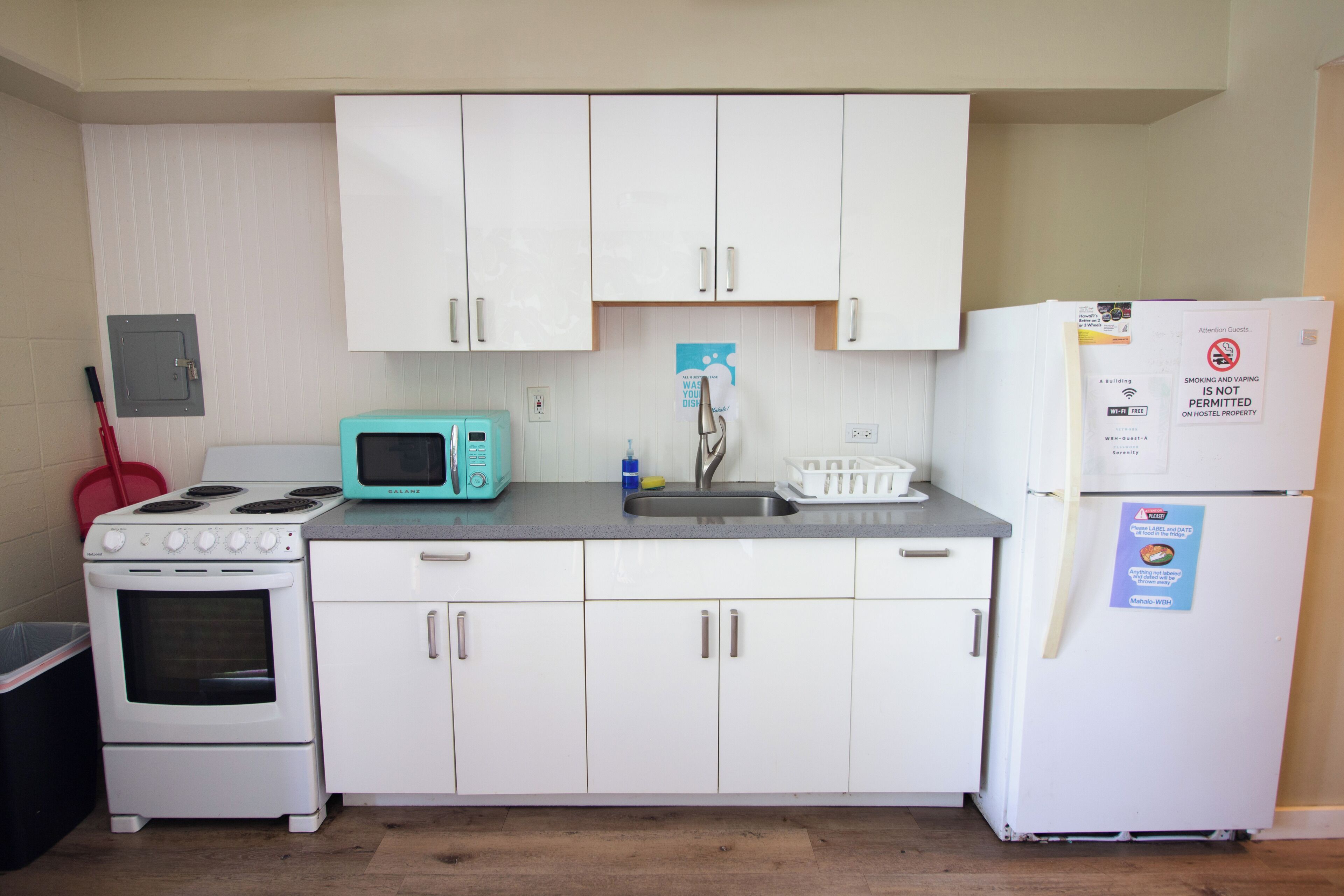 Una kitchenette compacta con armarios blancos, microondas, estufa y refrigerador.