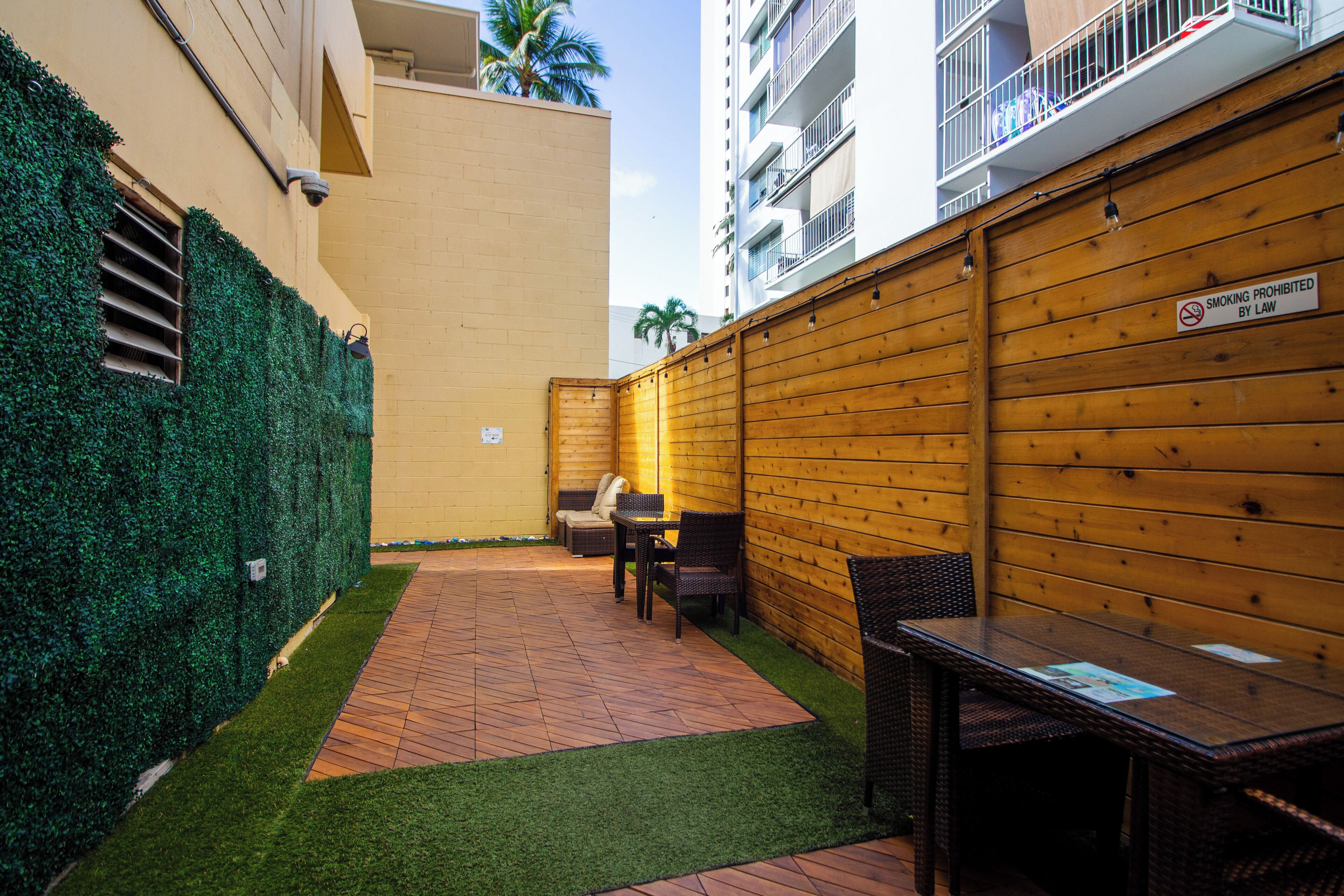 A patio area with a wooden fence, a small seating area with a table and chairs, and a sign indicating no smoking.