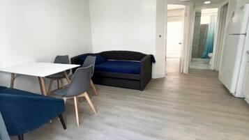 A compact living space with a dining area, a sofa, and a kitchenette.