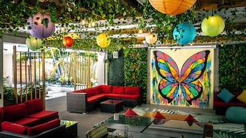 A modern lounge area with a red sofa, a glass coffee table, and a vibrant butterfly mural.