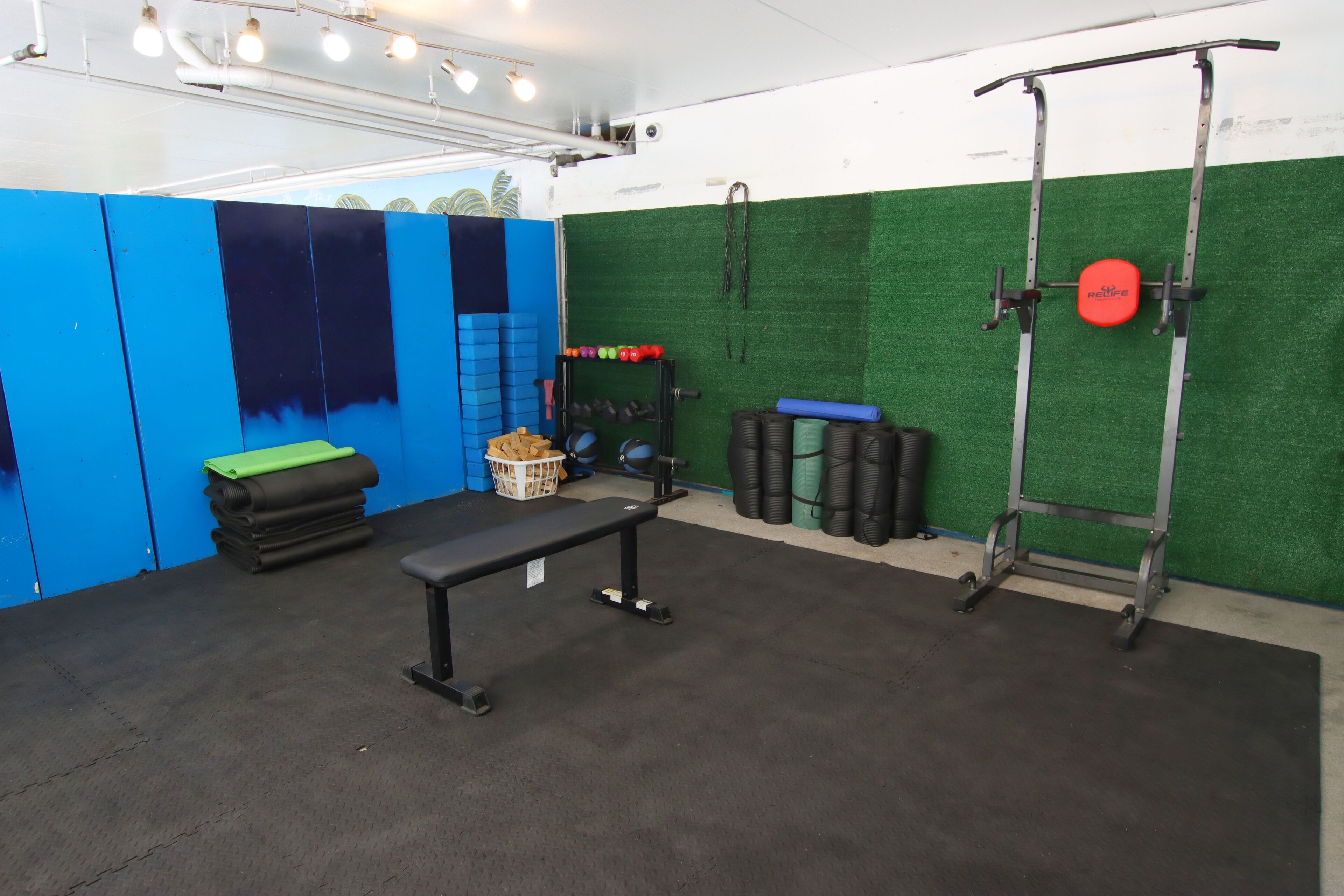 A gym with a bench, weight racks, and exercise balls.