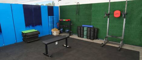 A gym with a bench, weight racks, and exercise balls.
