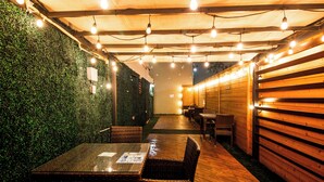 Ein Außenbereich mit Terrasse, Tisch, Stühlen, einer grünen Wand und Holzverkleidung.