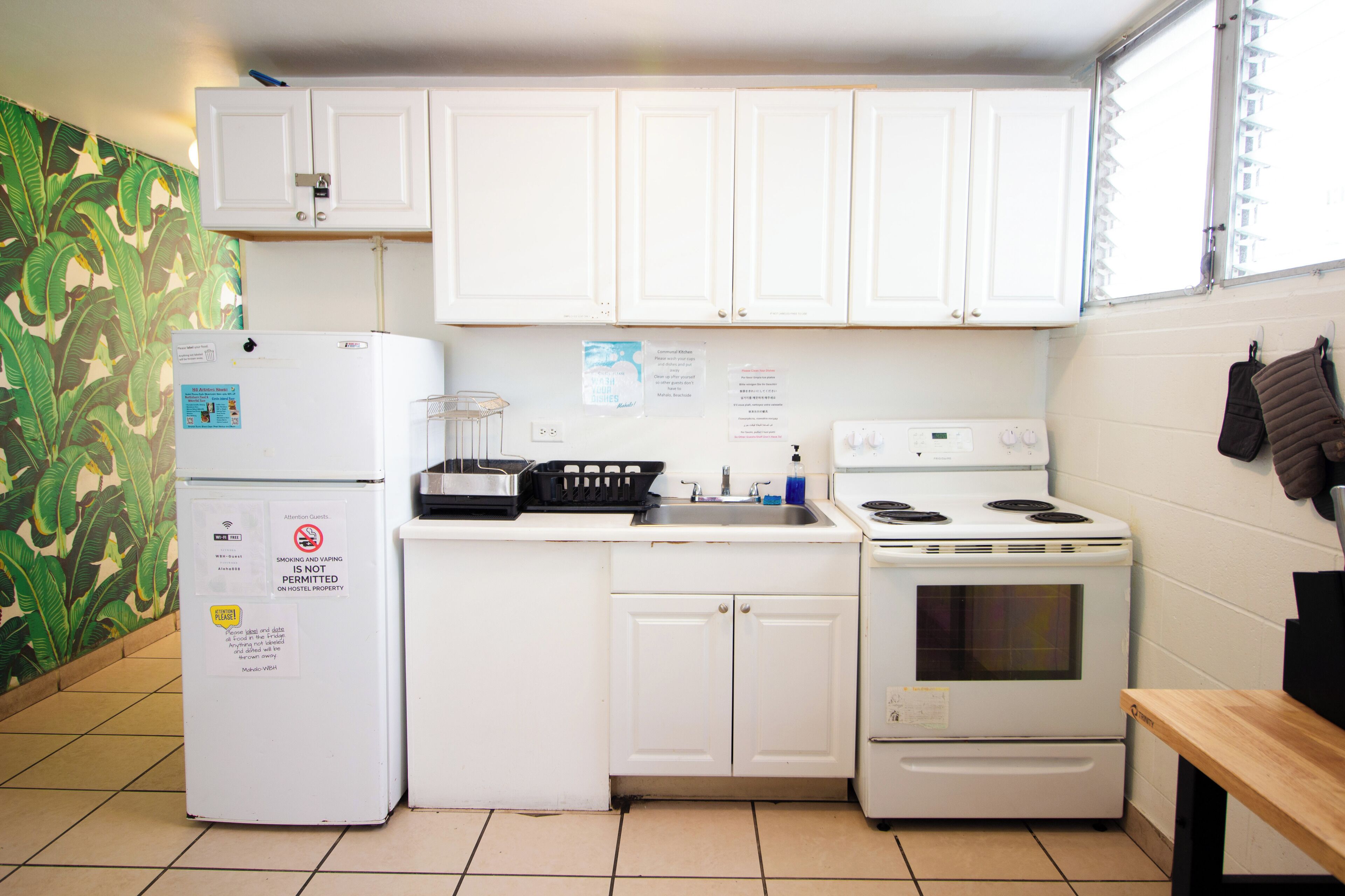 A compact kitchen with white cabinets, a refrigerator, a stove, and a sink.