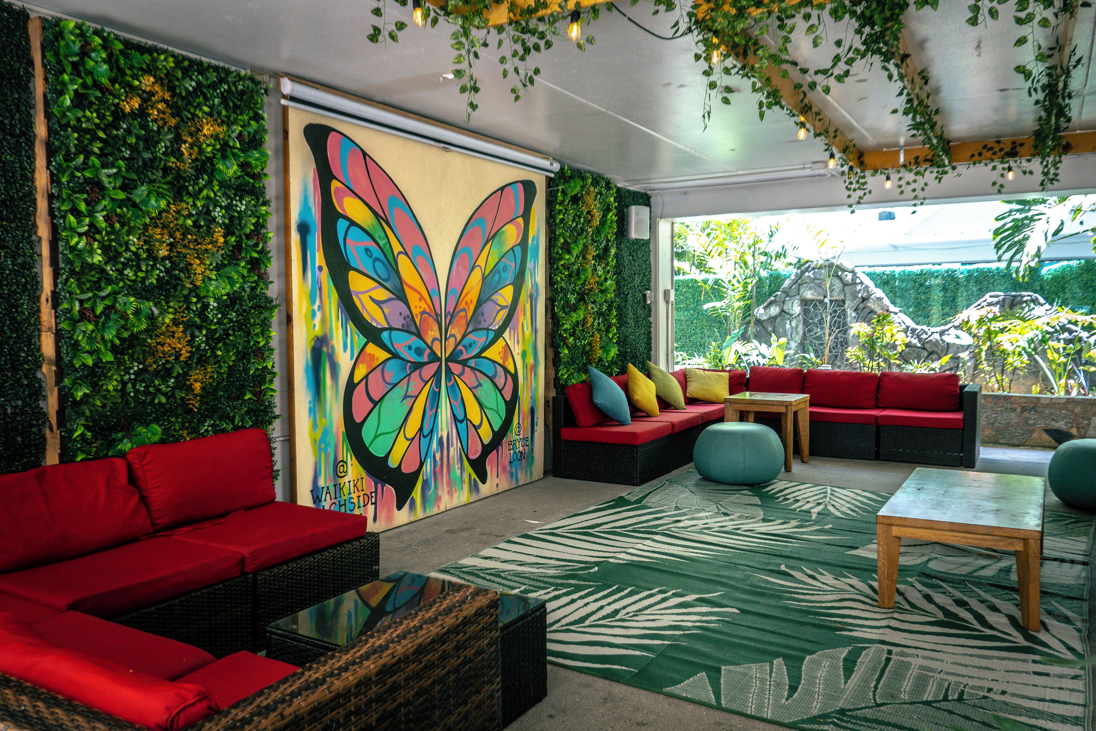 Un intérieur moderne agrémenté d’une grande fresque représentant des papillons, de sièges rouges et de murs d’un vert luxuriant.