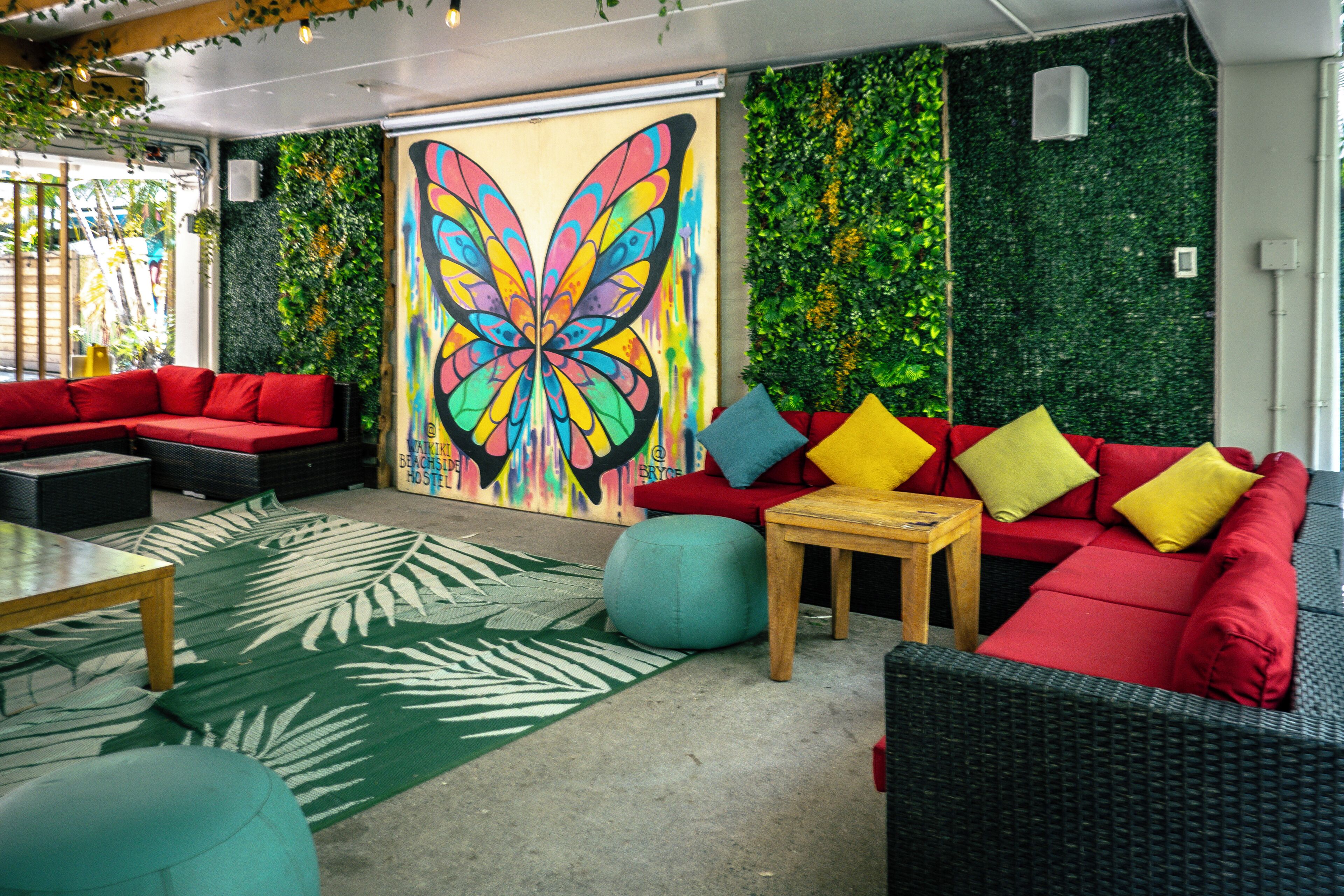 Un'area lounge moderna con divani, un tavolino e un murale con farfalle colorate.