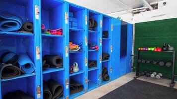 A gym with blue lockers containing mats and weights.
