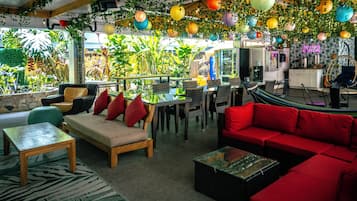 Un'accogliente zona salotto interna con un divano rosso, un tavolo in legno e un tappeto verde decorato.