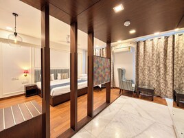 A modern hotel room with a large bed, a desk, a chair, and a view of the city.