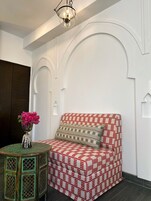 A room with a patterned sofa, a small table with a vase of flowers, and a decorative ceiling light.