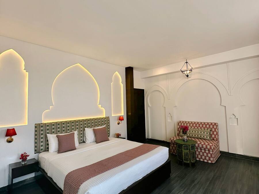 Una camera d'albergo moderna con un letto grande, un tavolino con una sedia e illuminazione decorativa a parete.