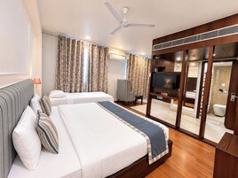 A hotel room with two beds, a TV, a ceiling fan, and a sliding door leading to a bathroom.