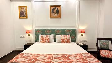 Een hotelkamer met een groot bed, twee nachtkastjes met lampen, een plafondventilator en twee ingelijste foto's aan de muur.