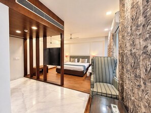 Une chambre d’hôtel moderne équipée d’un lit, d’une télévision, d’un canapé et d’une table basse en verre.