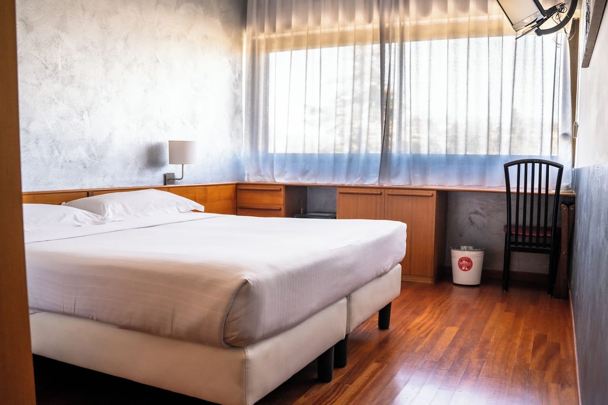 Une chambre à coucher comprenant un lit, un bureau, une chaise et une poubelle.