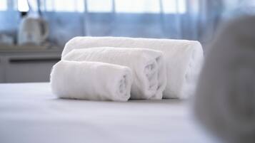 Two neatly folded white towels on a bed in a hotel room.