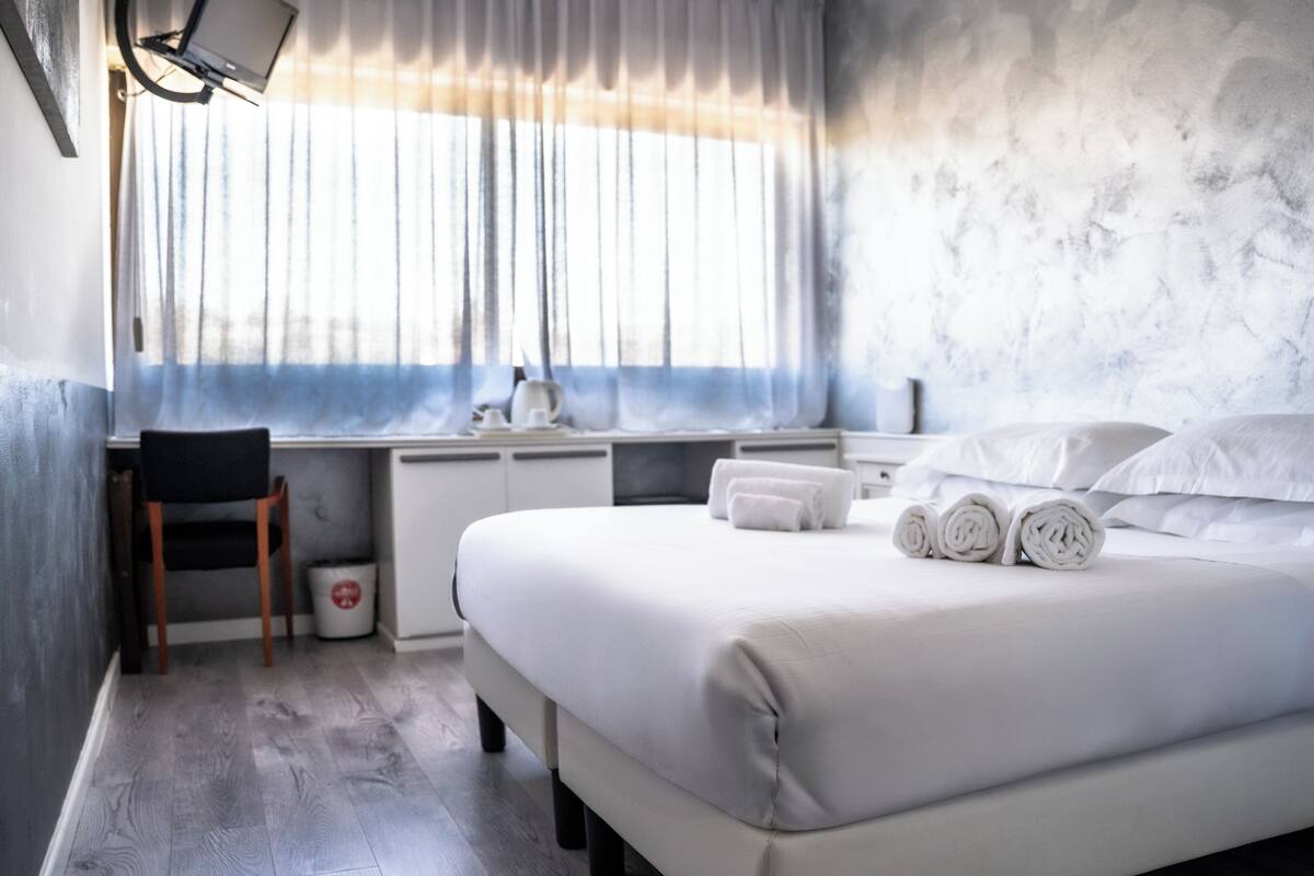 Une chambre d’hôtel moderne, dotée d’un grand lit, d’un bureau et d’une chaise.