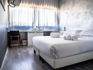 Une chambre d’hôtel moderne, dotée d’un grand lit, d’un bureau et d’une chaise.