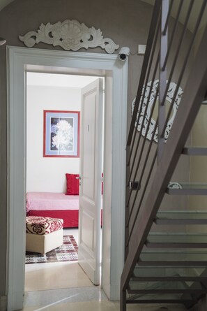 A doorway leading to a bedroom with a bed, a red pillow, and a framed picture on the wall. - B&B Rossocorallo (Catania)