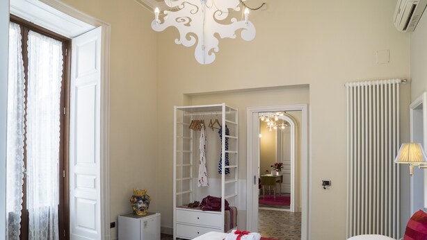 A hotel room with a bed, a wardrobe, a small table, and a mirror. - B&B Rossocorallo (Catania)