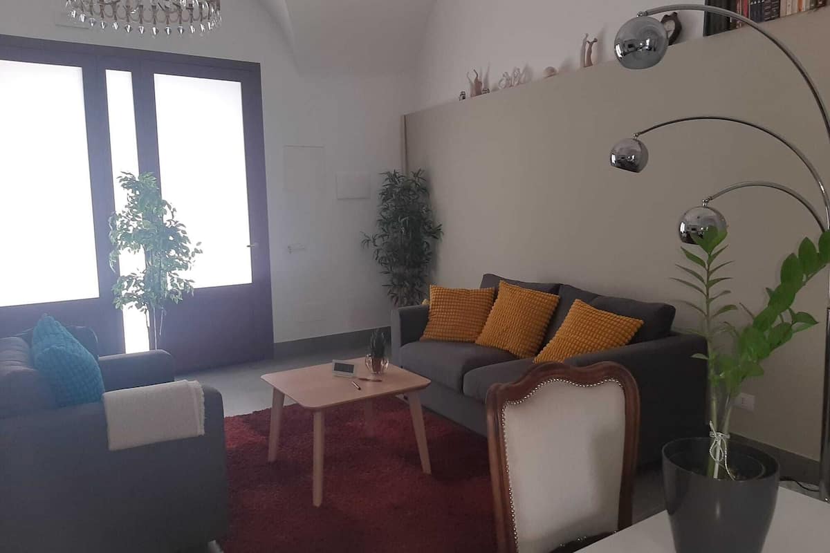 A living room with a sofa, a coffee table, a potted plant, and a lamp.