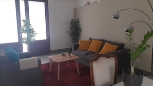 A living room with a sofa, a coffee table, a potted plant, and a lamp. - B&B Rossocorallo (Catania)