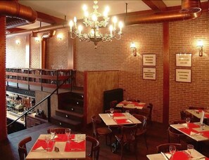 A restaurant with brick walls, a chandelier, and tables set for dining. - Hotel Madrid Rio (Madrid)