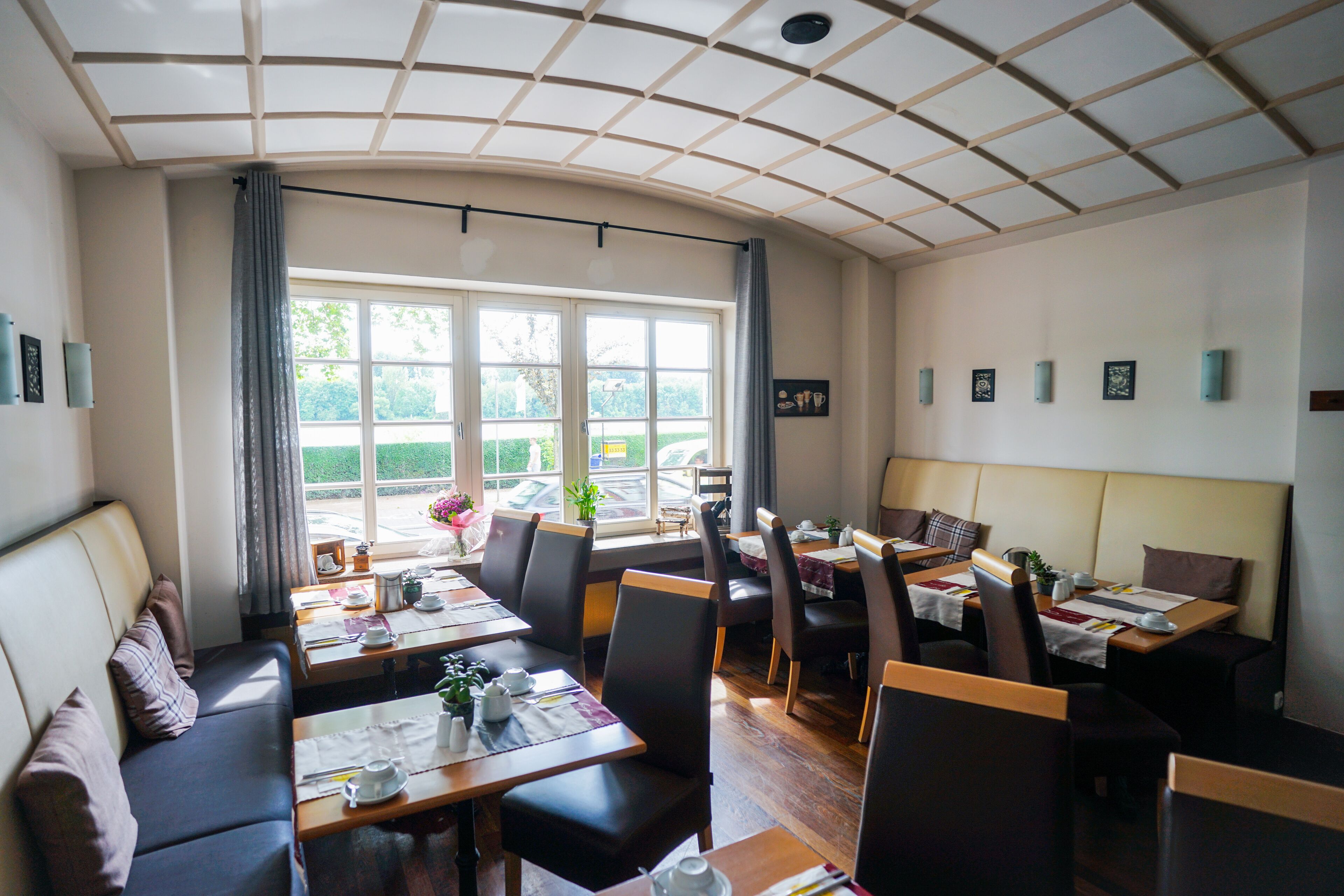 Ein Restaurant mit gewölbter Decke, großen Fenstern und verschiedenen Sitzmöglichkeiten, darunter Tische und eine Couch.
