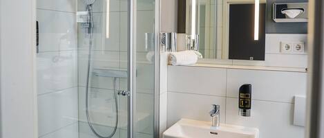 A modern bathroom with a glass-enclosed shower, a white sink, and a mirror above the sink.