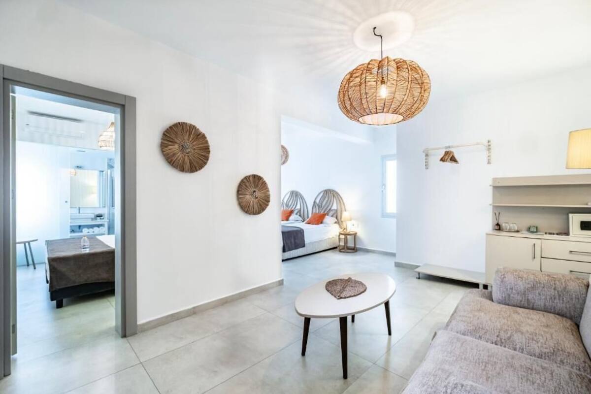 A modern living room with a sofa, a round coffee table, and a hanging light fixture.