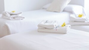 A hotel room with neatly folded towels on the bed and a stack of towels on the side. - Hispano Boutique Gran Vía (Madrid)