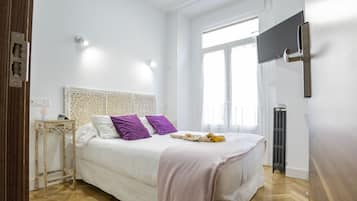Un dormitorio con cama, mesita de noche, radiador y ventana.