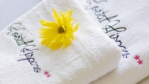 Two folded towels with embroidered text and a yellow flower. - Hispano Boutique Gran Vía (Madrid)