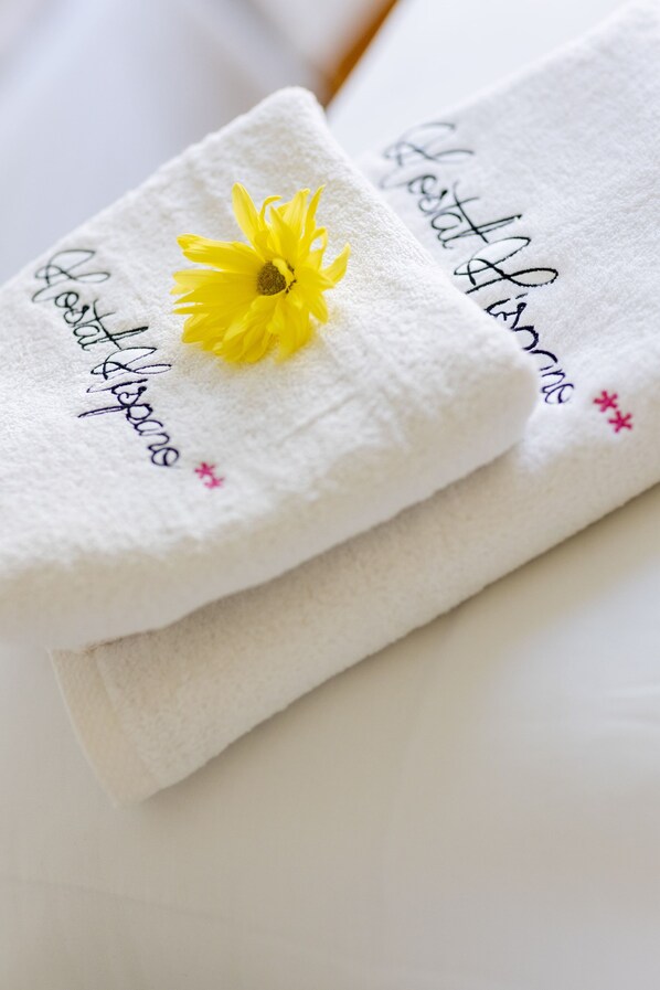 Two folded towels with embroidered text and a yellow flower.