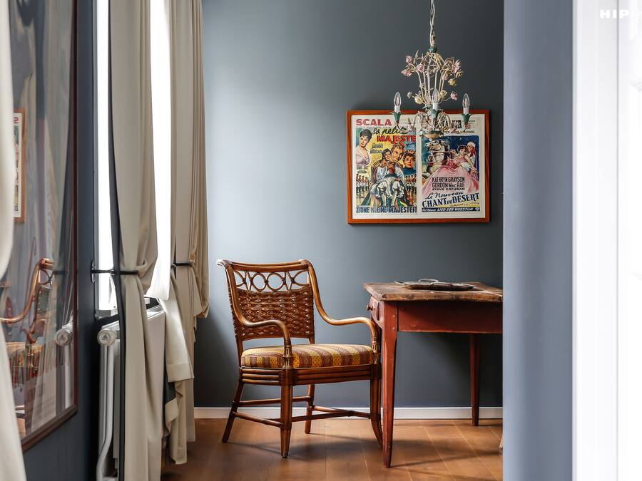 Una habitación con una silla de madera, una mesa y un cartel enmarcado en la pared.