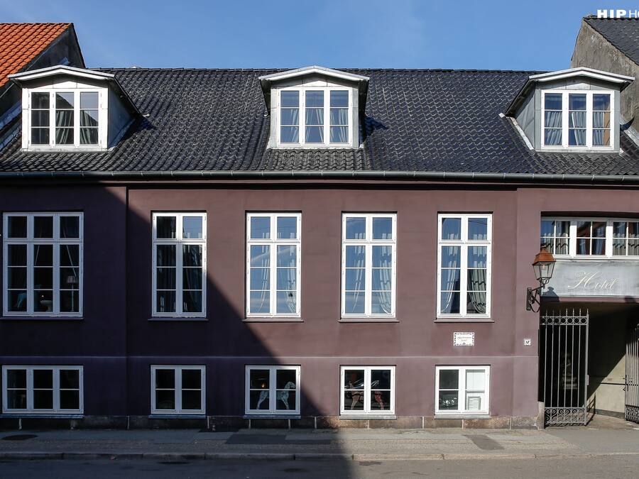 A hotel with a dark facade, multiple windows, and a prominent entrance with a sign.