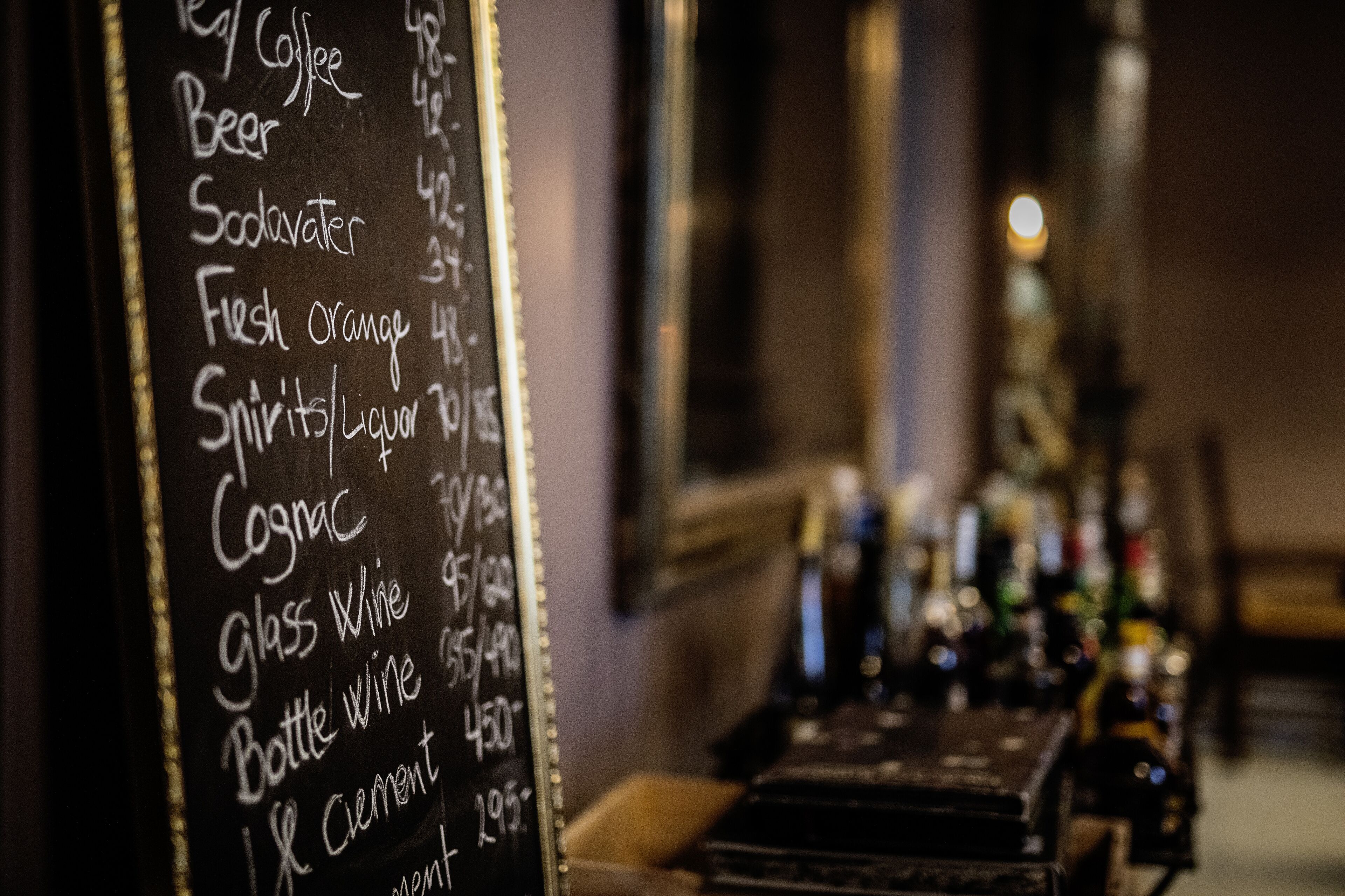 Zona de bar con un menú en pizarra que detalla bebidas y precios.