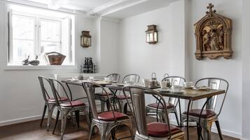 A dining area with a wooden table and metal chairs, a window with a view, and a wall-mounted clock.