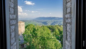 A stone archway framing a view of a mountainous landscape with a tower. - Balkoni Zagoriou (Zagori)