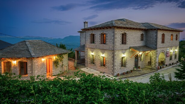 A stone building with multiple windows and a balcony, surrounded by greenery. - Balkoni Zagoriou (Zagori)