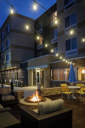 An outdoor patio area with a fire pit, seating, and string lights. - Fairfield Inn & Suites by Marriott Fayetteville North (Fayetteville)