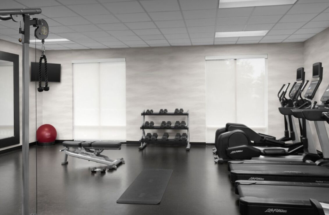 Une salle de sport équipée de tapis de course, d’haltères et d’un vélo d’appartement.