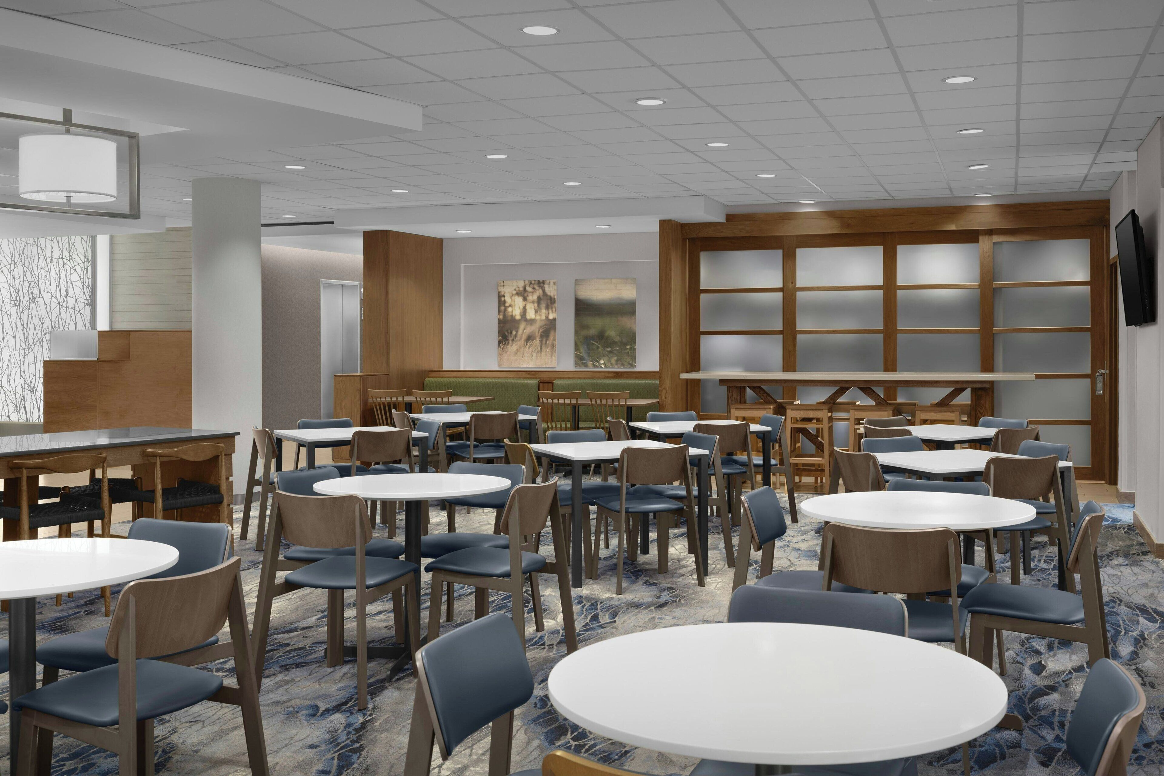 A hotel lobby with round tables and chairs, a reception area, and artwork on the walls.