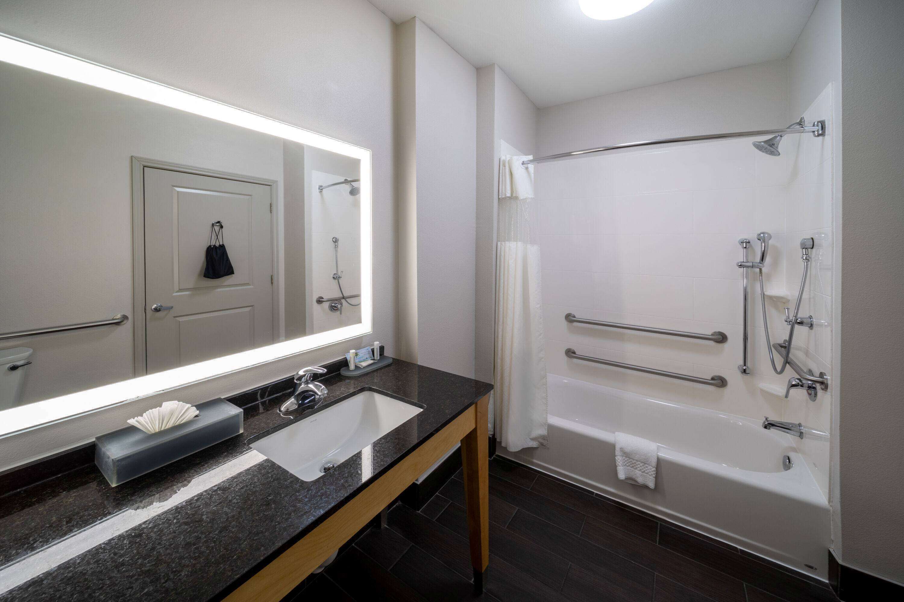 Une salle de bain avec un lavabo, un miroir et une baignoire.