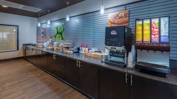 A modern hotel lobby with a long reception counter, a coffee machine, and a refrigerated drink dispenser.